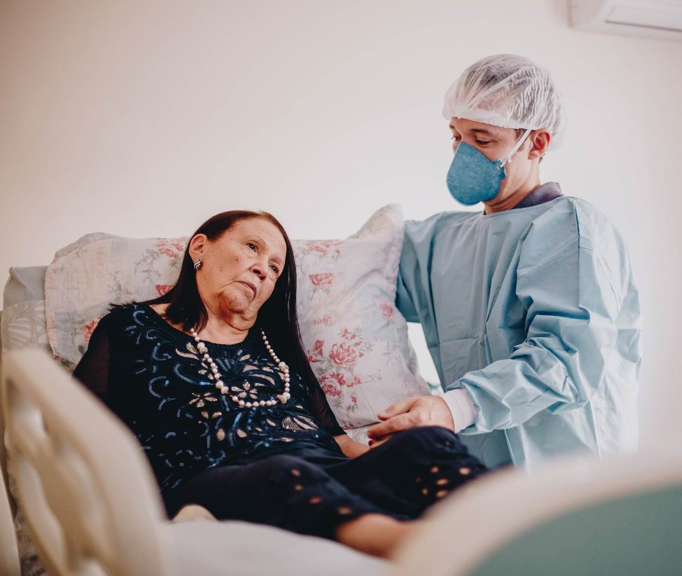 Dentista atendendo paciente idosa em casa, segurando sua mao com carinho